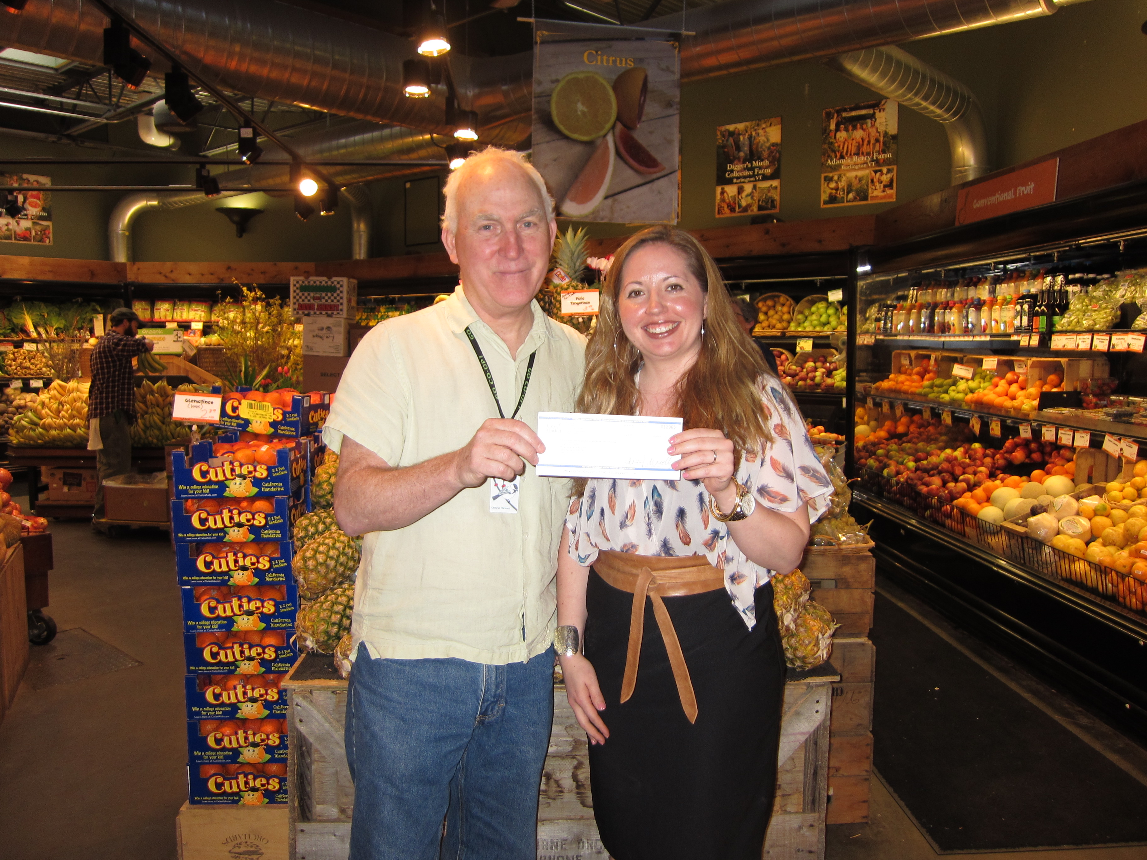 Clem Nilan, General Manager of City Market, presents a donation check to Marissa Parisi, Executive Director of Hunger Free Vermont. Clem Nilan, General Manager of City Market, presents a donation check to Marissa Parisi, Executive Director of Hunger Free Vermont.